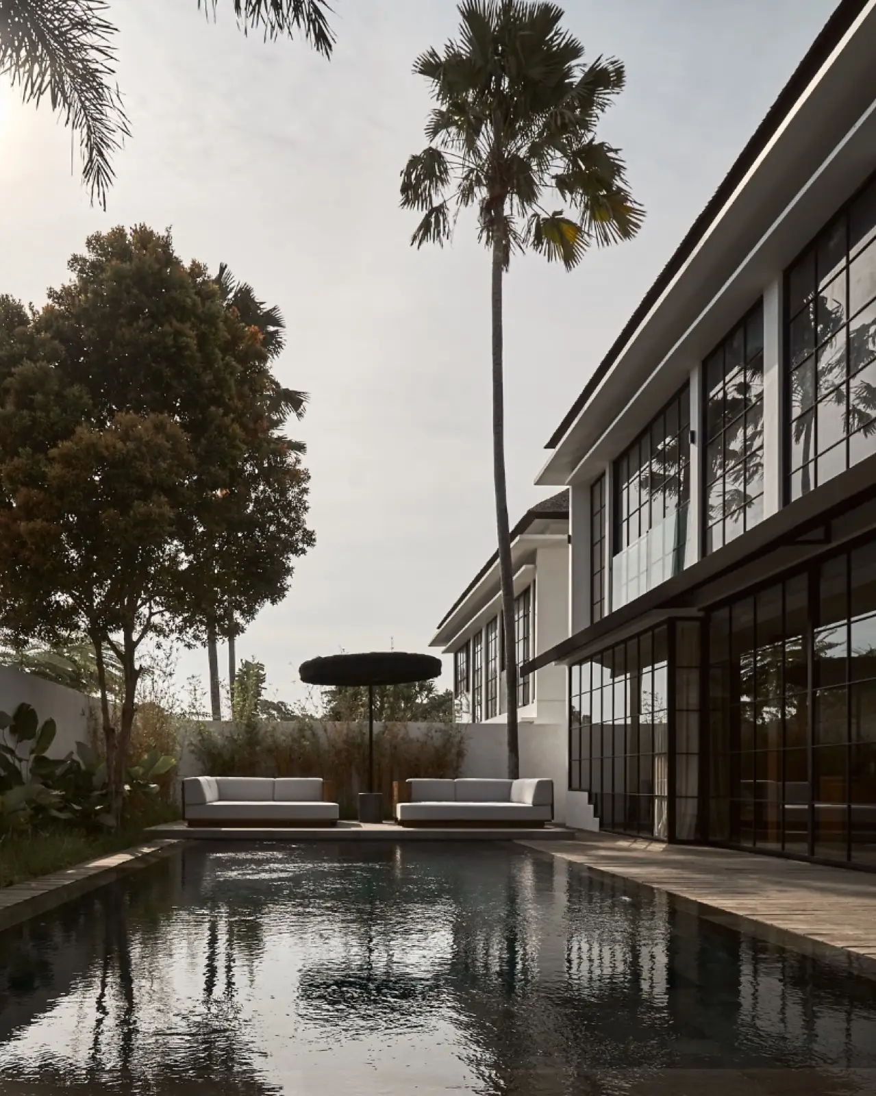 The twin Umalas villas at dusk with dark-framed glazing and pool