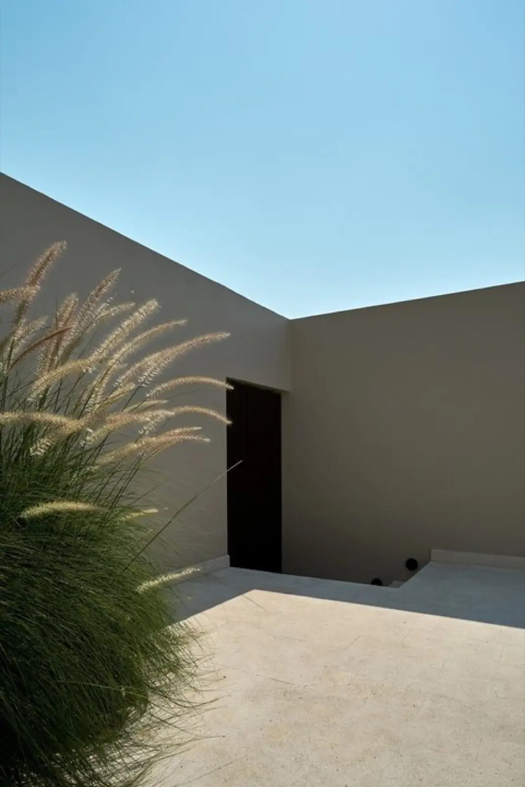 Minimal rendered wall and timber entrance door at Vesna, Berawa