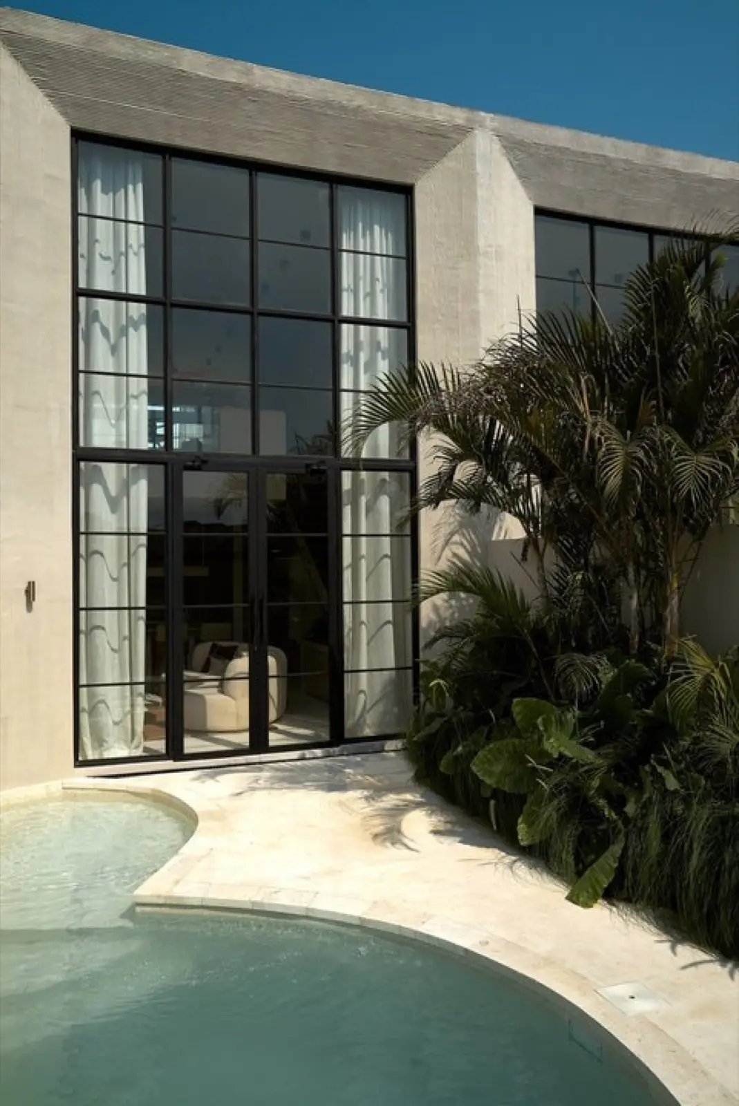 Black-framed window wall and mature planting at the Vesna complex